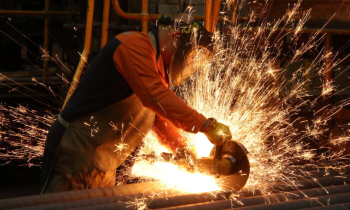A worker cuts newly manufactured bars of steel at the United Cast Bar Group's foundry in Chesterfield, Britain, on April 12, 2022.  (Phil Noble/Reuters)