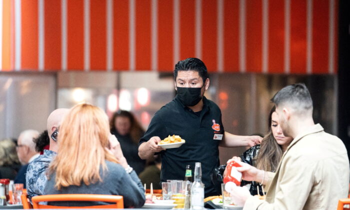 A waiter serves food at a restaurant near Times Square in New York, on Dec. 16, 2021. (Jeenah Moon/Reuters)