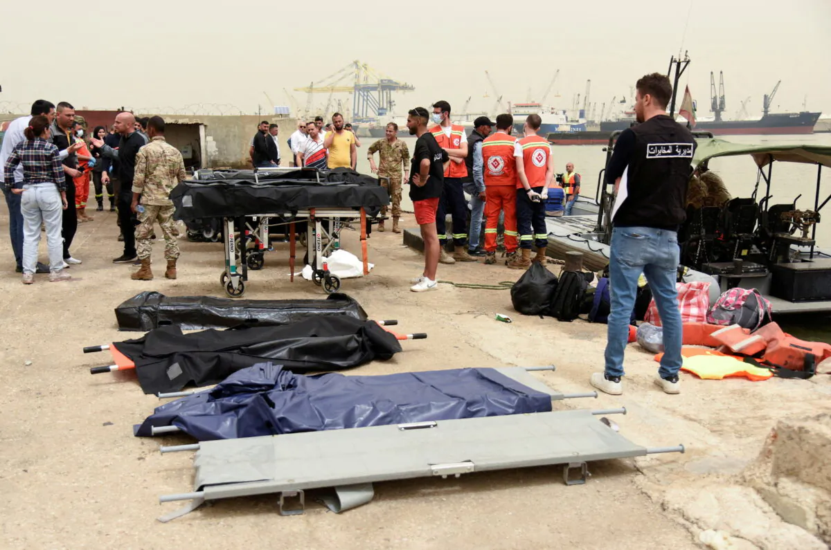 People stand near stretchers that are prepared for dead bodies after a boat capsized off the Lebanese coast of Tripoli overnight, at port of Tripoli, northern Lebanon, on April 24, 2022. (Omar Ibrahim/Reuters)