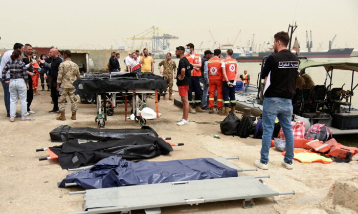 People stand near stretchers that are prepared for dead bodies after a boat capsized off the Lebanese coast of Tripoli overnight, at port of Tripoli, northern Lebanon, on April 24, 2022. (Omar Ibrahim/Reuters)