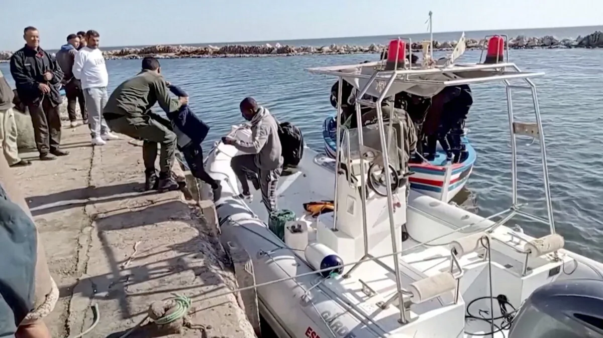 A Tunisian national coast guard helps a migrant child to get off a rescue boat in Jbeniana, Safx, Tunisia, on April 23, 2022, in this screengrab taken from a handout video taken April 23, 2022. (Wahid Dahech/ Handout via Reuters)
