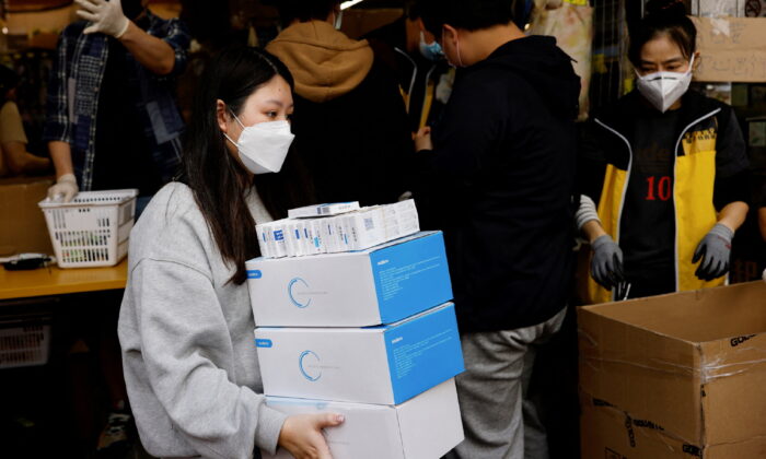 A woman wearing a protective mask buys boxes of Rapid antigen test kits for COVID-19 in Hong Kong, on Feb. 28, 2022. (Tyrone Siu/Reuters)