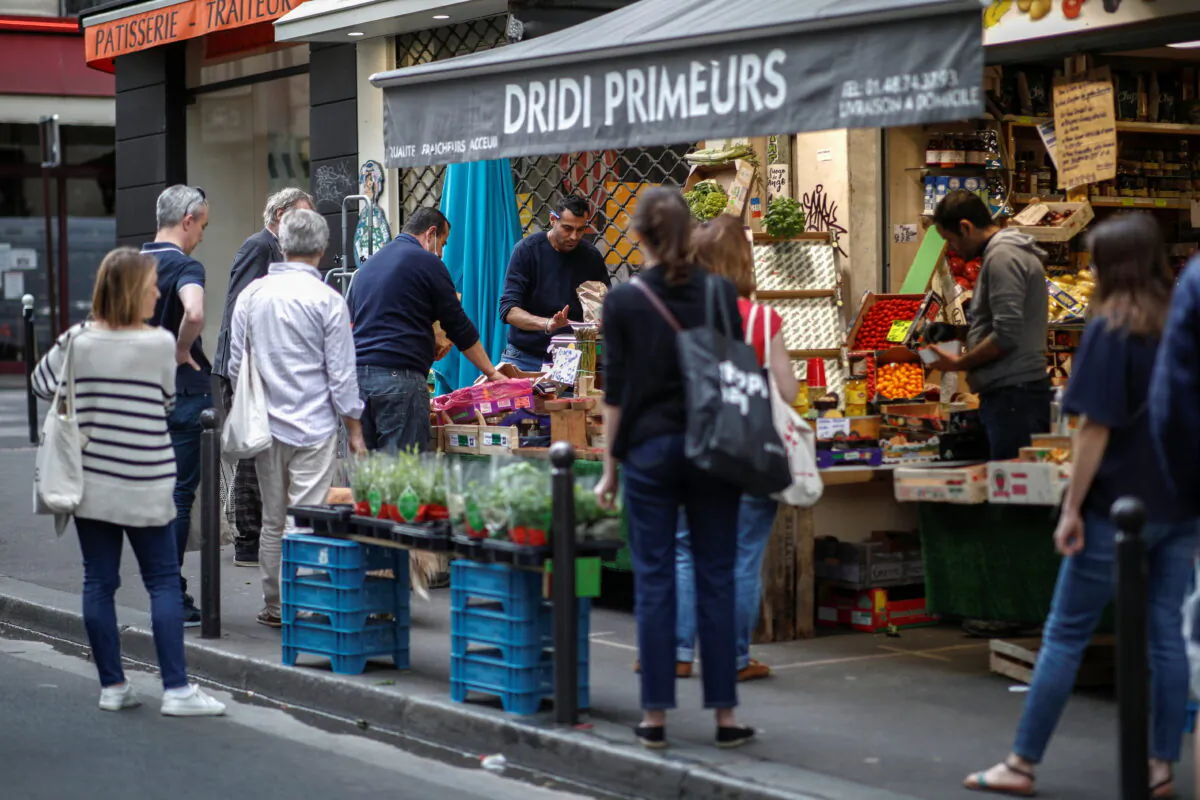 People queue in front of a fruit and vegetables shop at Rue des Martyrs in Paris, on April 18, 2020. (Benoit Tessier/Reuters)