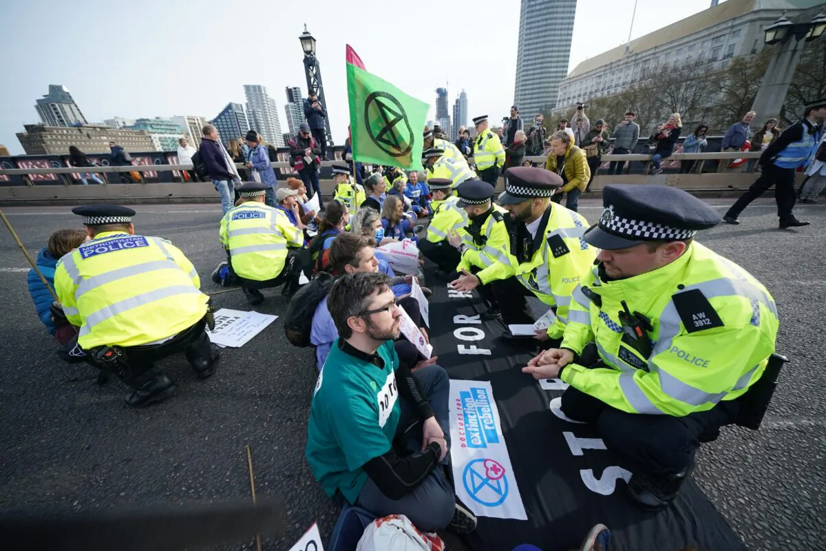 Police talk to protesters taking part in a demonstration on Lambeth Bridge in central London, on April 10, 2022. (Yui Mok/PA)