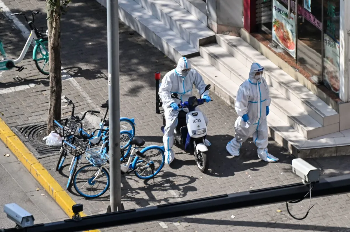Officers wearing personal protective equipment walk next to the entrance of a neighborhood during a COVID-19 lockdown in the Jing'an district in Shanghai on April 8, 2022. (Hector Retamal/AFP via Getty Images)