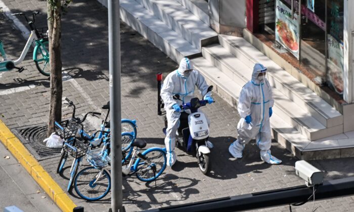 Officers wearing personal protective equipment walk next to the entrance of a neighborhood during a COVID-19 lockdown in the Jing'an district in Shanghai on April 8, 2022. (Hector Retamal/AFP via Getty Images)