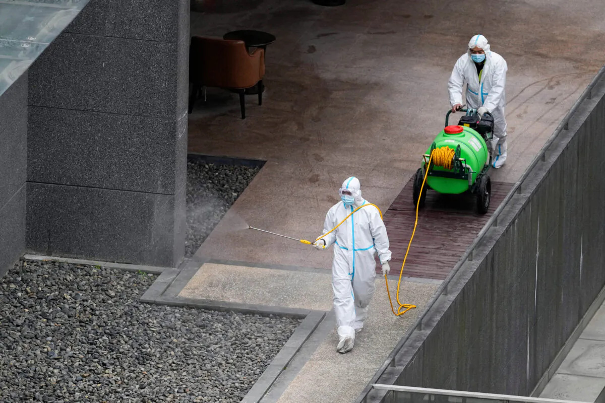 Workers in protective suit spray disinfectant at a community during the lockdown in Shanghai on April 5, 2022. (Aly Song/Reuters)