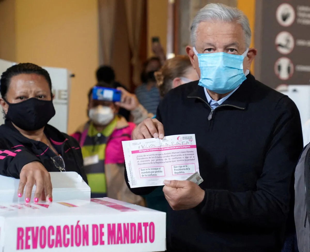 Mexican President Andres Manuel Lopez Obrador (R) shows his ballot for the recall referendum on his presidency in Mexico City, on April 10, 2022. (Mexico Presidency/Handout via Reuters)