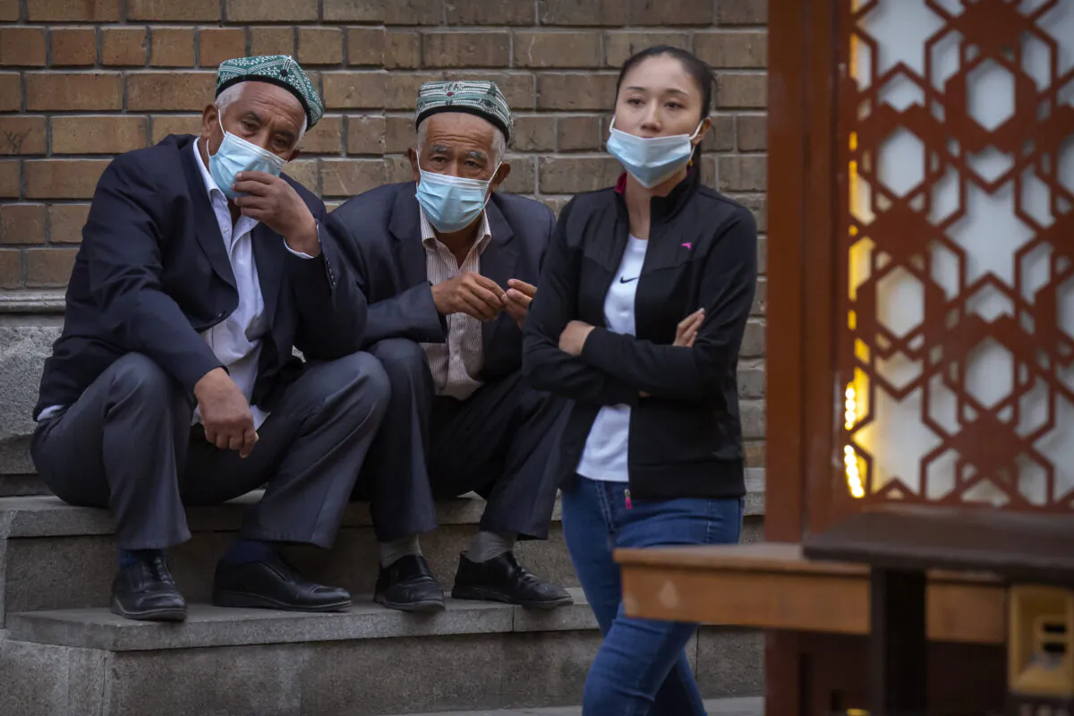 Uyghur men sitting on steps in Urumqi in western China's Xinjiang Uyghur Autonomous Region on  April 21, 2021. (Mark Schiefelbein/AP)