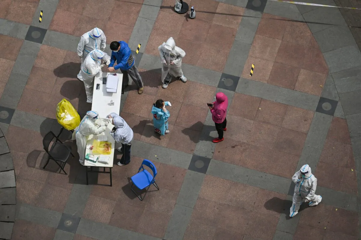 A health worker wearing personal protective equipment (bottom left) takes a swab for COVID-19 testing in a compound during a lockdown in the Jing'an district in Shanghai on April 10, 2022. (Hector Retamal/AFP via Getty Images)