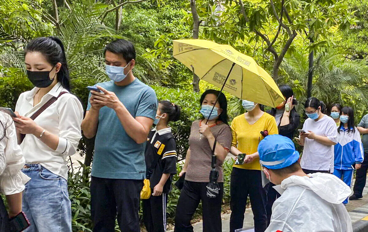 Workers in protective gear watch over residents line up for the COVID-19 test at a residential block in Guangzhou, China, on April 11, 2022. (Chinatopix via AP)