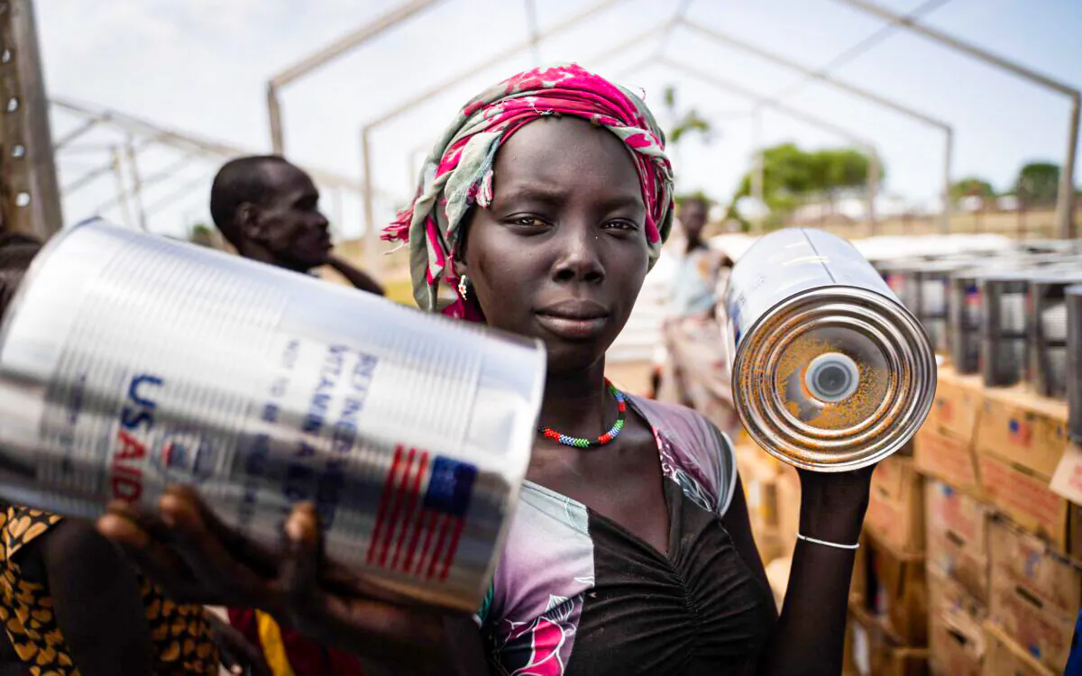 A woman from Murle ethnic group receives cans of oil during a food distribution by United Nations World Food Programme (WFP) in Gumuruk, South Sudan, on June 10, 2021, after her village was recently attacked by an armed youth group. (Simon Wohlfahrt/AFP via Getty Images)