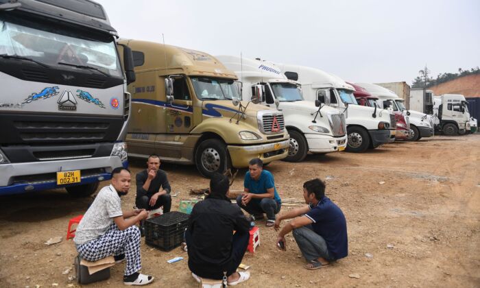 Truck drivers gather at a makeshift parking lot where Vietnamese container trucks are waiting to cross the Vietnam-China border in Lang Son Province on Jan. 7, 2022, as thousands of trucks carrying fruit remained stuck at the border while China tightened its border policies. (STR/AFP via Getty Images)