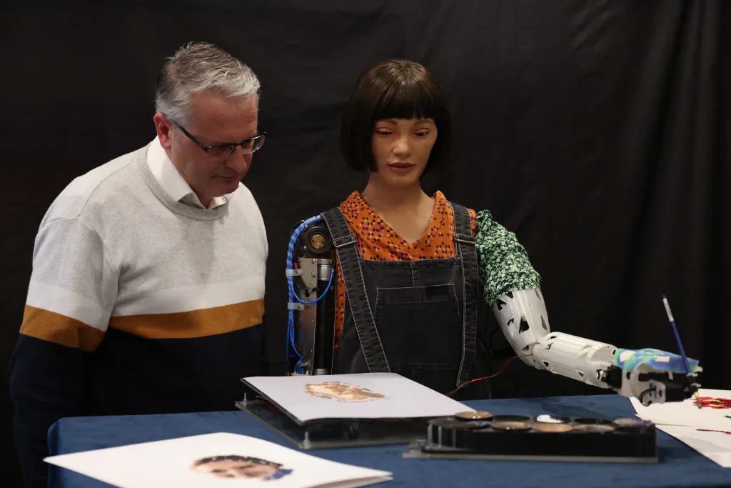 Aidan Meller looks at a painting by Ai-Da Robot, an ultra-realistic humanoid robot artist, during a press call at the British Library in London, on April 4, 2022. (Hollie Adams/Getty Images)