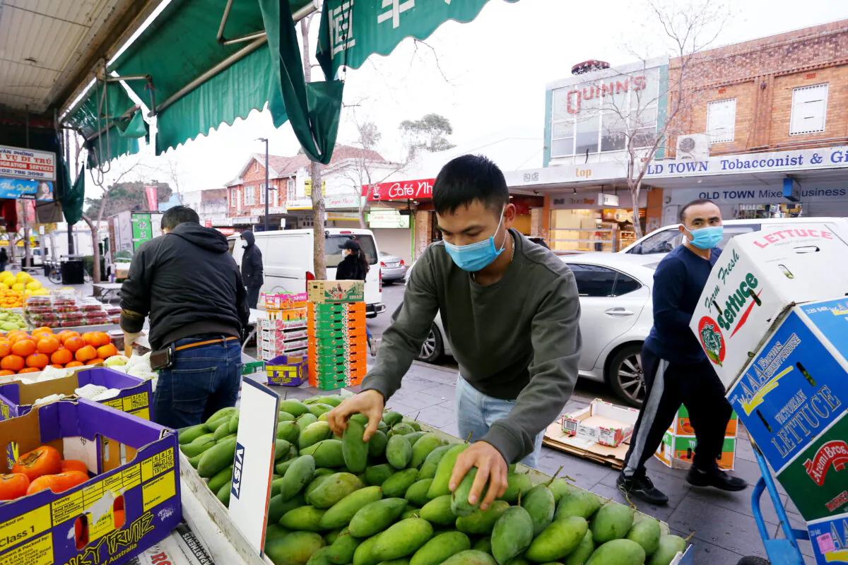 Workers wear face masks as they set up displays at a local fruit and vegetable market  in Sydney, Australia, on July 9, 2021. (Lisa Maree Williams/Getty Images)