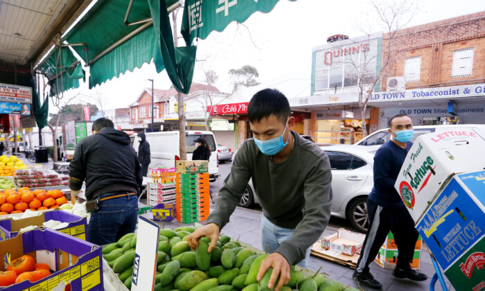 Workers wear face masks as they set up displays at a local fruit and vegetable market  in Sydney, Australia, on July 9, 2021. (Lisa Maree Williams/Getty Images)