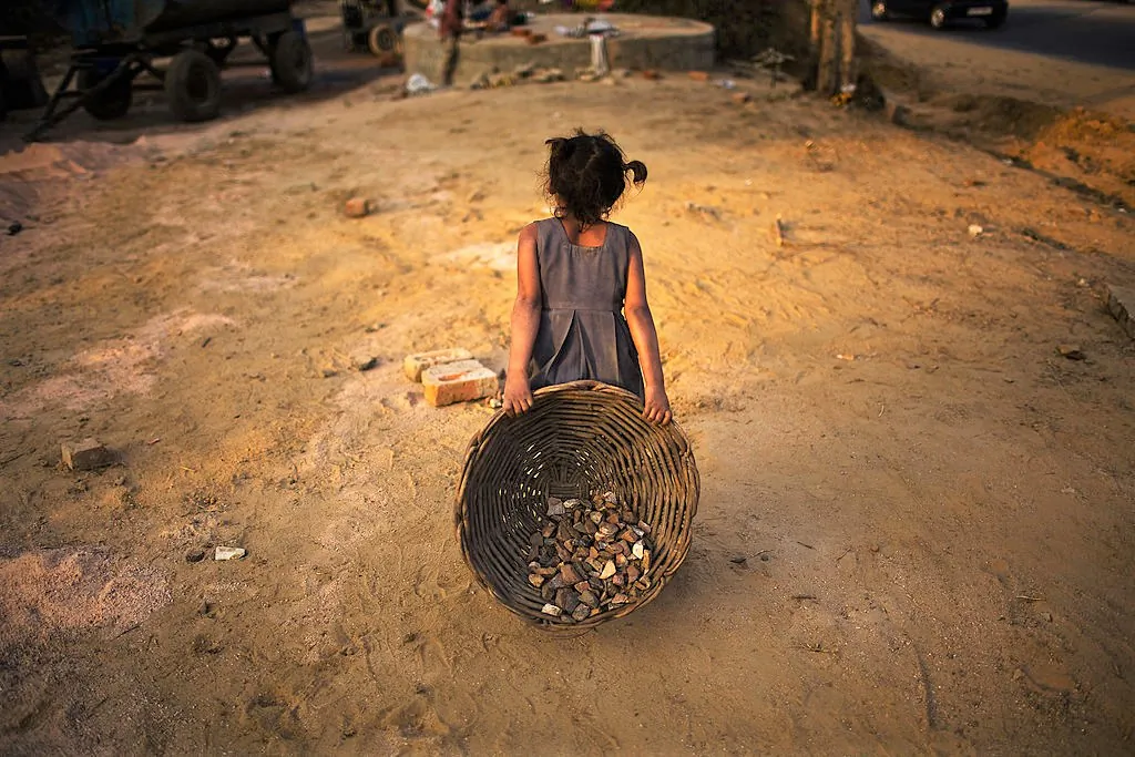 Indian children work nearby to their parents at a construction project in front of the Jawaharlal Nehru Stadium in New Delhi, India, on Jan. 30, 2010. (Daniel Berehulak/Getty Images)