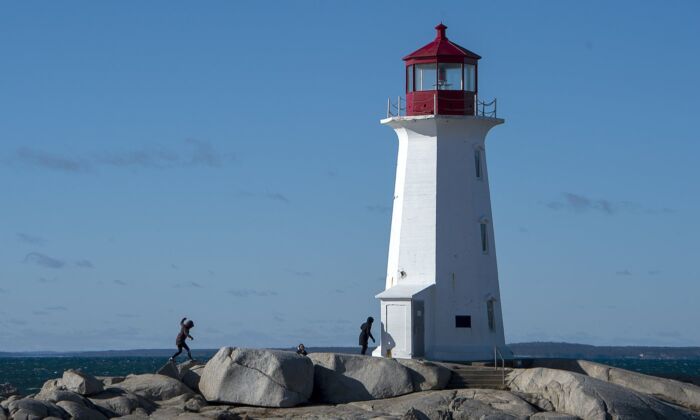 Visitors walk on the rocks in Peggys Cove, N.S. on Jan. 19, 2021. (The Canadian Press/Andrew Vaughan)