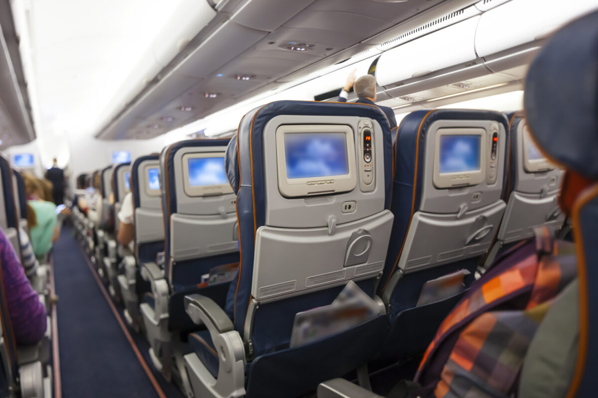 Seating space with multimedia screens economy class airplane. (Dreamstime)