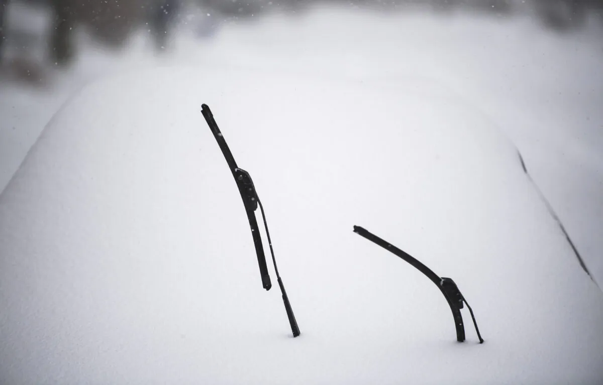 Raised windshield wiper blades are seen above a blanket of snow covering a car in Ottawa, on Jan. 17, 2022. (The Canadian Press/Justin Tang)