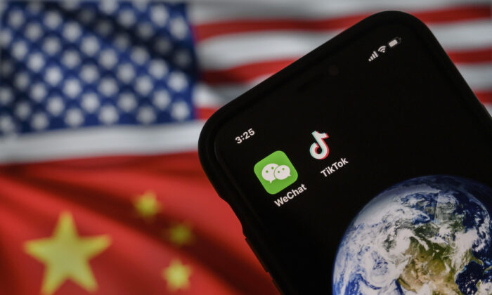 2020 年 9 月 22 日，中国北京，一部手机在互联网页面上显示美国和中国国旗的显示器前显示中国应用程序微信和 TikTok 的徽标。  （凯文弗雷尔/盖蒂图片社）