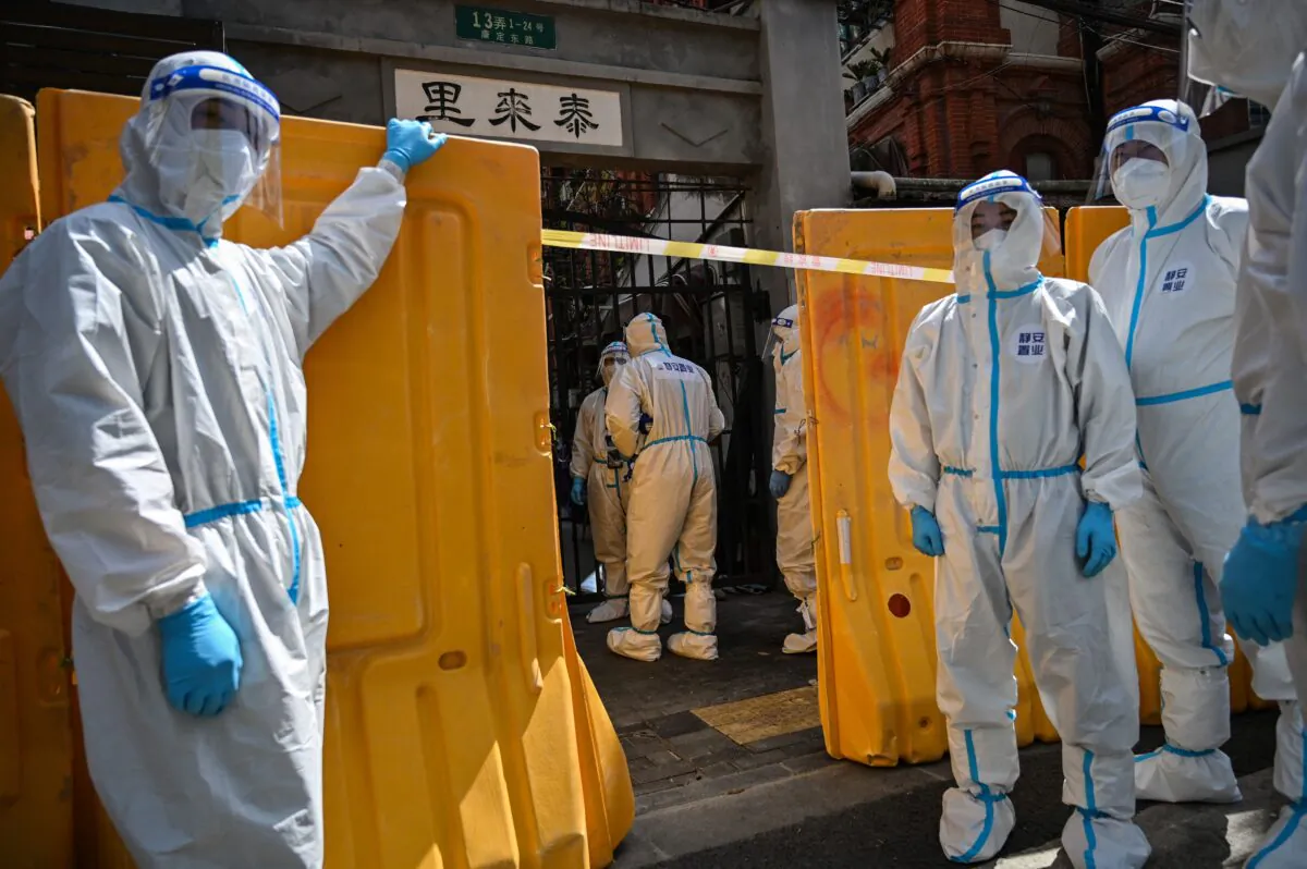 Workers from a public service organization, wearing protective gear, deliver vegetables to residents of a neighborhood in lockdown in Jing'an district, in Shanghai on March 29, 2022. (Hector Retamal/AFP via Getty Images)