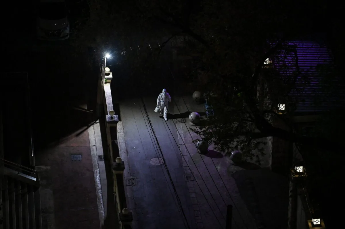 A worker, wearing personal protective equipment (PPE), walks on a street at night during a COVID-19 lockdown in the Jing'an district in Shanghai on April 10, 2022. (Hector RetamalL/AFP via Getty Images)