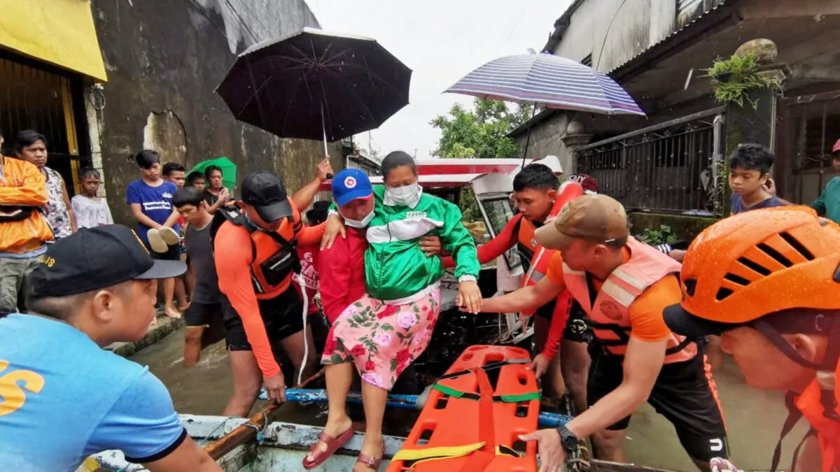 Rescue personnel assist a woman onto a raft amidst flooding, after the tropical storm Megi hit, in Leyte Province, Philippines April 10, 2022. Picture taken April 10, 2022. (Philippine Coast Guard/Handout via Reuters)
