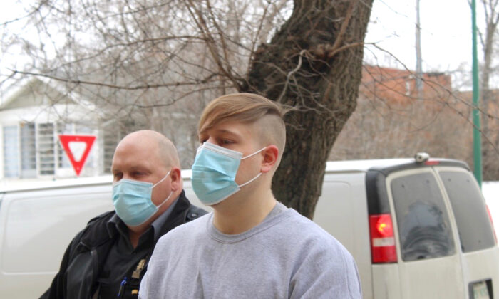 Nathaniel Carrier, accompanied by an unidentified sheriff, is seen exiting a police van on his way to Prince Albert Court of Queen's Bench on April 13, 2022. Carrier has been sentenced to life in prison with no chance of parole for 25 years for killing his parents and seven-year-old son in March 2020. He also pleaded guilty to the attempted murder of his daughter, who was five at the time. (The Canadian Press/Nigel Maxwell)