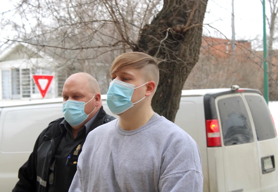 Nathaniel Carrier, accompanied by an unidentified sheriff, is seen exiting a police van on his way to Prince Albert Court of Queen's Bench on April 13, 2022. Carrier has been sentenced to life in prison with no chance of parole for 25 years for killing his parents and seven-year-old son in March 2020. He also pleaded guilty to the attempted murder of his daughter, who was five at the time. (The Canadian Press/Nigel Maxwell)