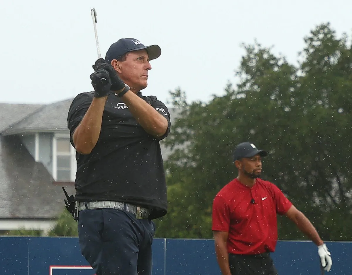 Phil Mickelson (L) plays his shot from the first tee as Tiger Woods looks on during The Match: Champions for Charity golf round at the Medalist Golf Club in Hobe Sound, Fla., on May 24, 2020. (Mike Ehrmann/Getty Images for The Match)