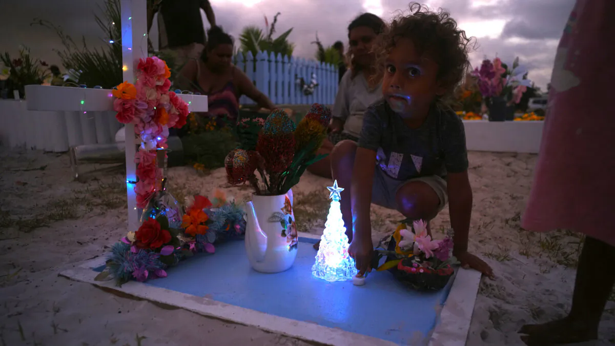 Children play with fairy lights at a decorated grave site at Hope Vale cemetery. (Courtesy Caden Pearson)