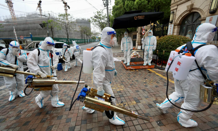 People in protective suits prepare to disinfect a residential compound to curb the spread of COVID-19 in Huangpu district, Shanghai, China, on April 14, 2022. (China Daily via Reuters)
