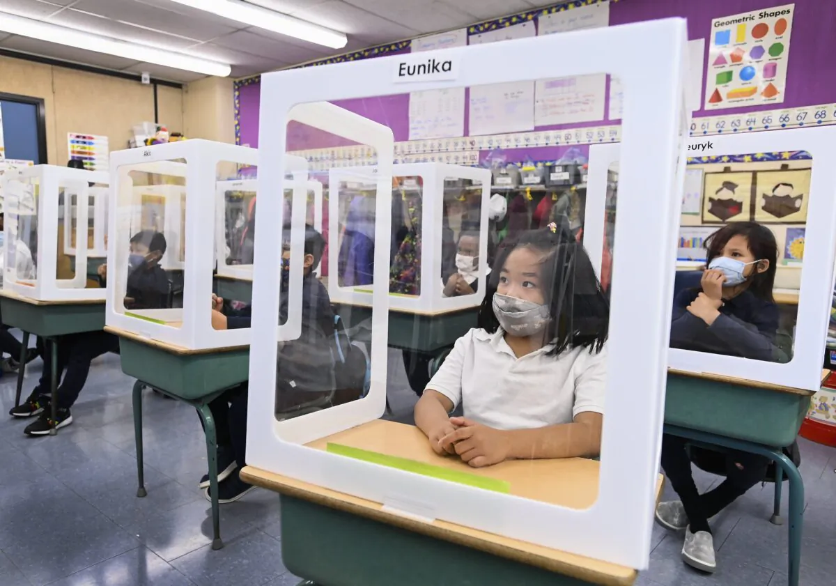 Children wearing masks sit behind screened in cubicles as they learn in their classroom at St. Barnabas Catholic School during the COVID-19 pandemic in Scarborough, Ont., on Oct. 27, 2020. (Nathan Denette/The Canadian Press)
