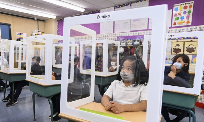 Children wearing masks sit behind screened in cubicles as they learn in their classroom at St. Barnabas Catholic School during the COVID-19 pandemic in Scarborough, Ont., on Oct. 27, 2020. (Nathan Denette/The Canadian Press)