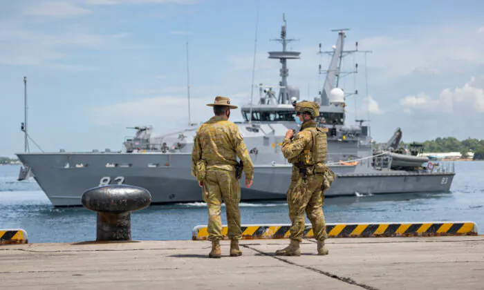 In this handout provided by the Australian Department of Defence, Commander of Joint Task Group 637.3, Lieutenant Colonel Steve Frankel (left), and Private Thomas Rixon, watch the Armidale Class Patrol Boat, HMAS Armidale, sail into the Port of Honiara, in Guadalcanal Island, Solomon Islands, on Dec. 1, 2021. (CPL Brandon Grey/Australian Department of Defence via Getty Images)