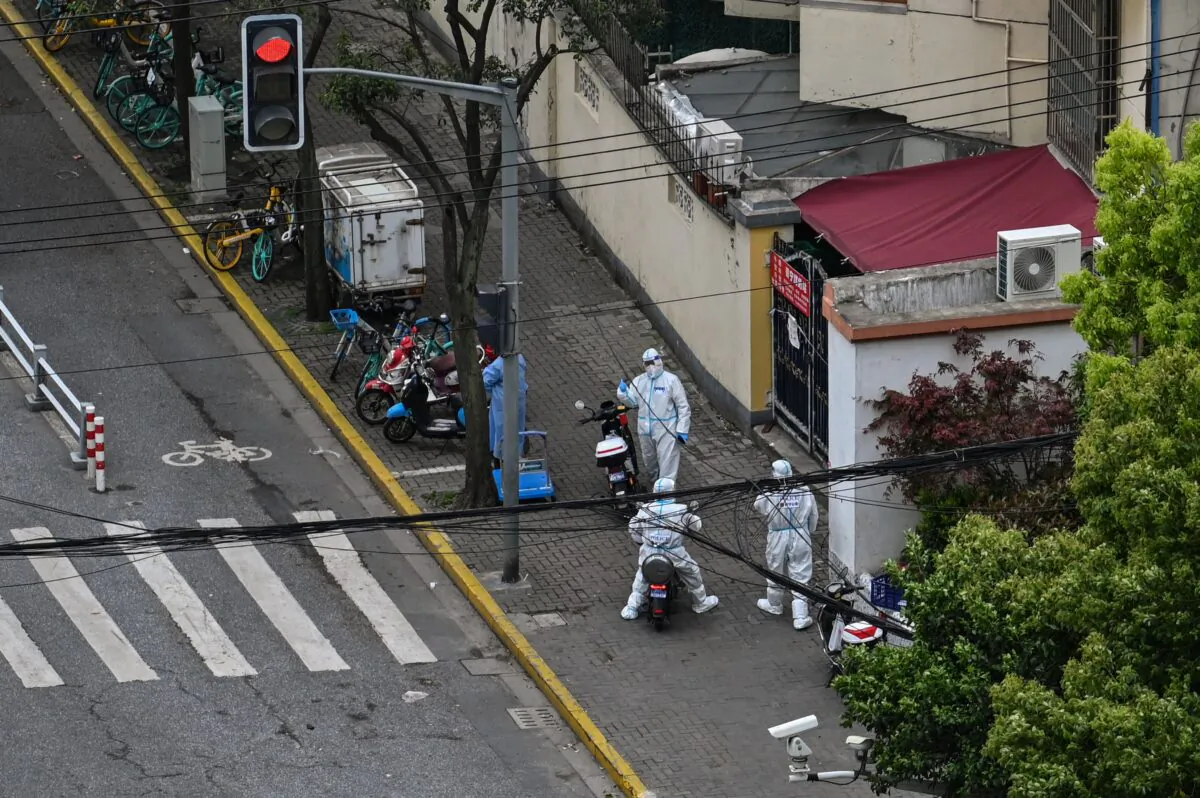 Policemen in personal protective equipment stand next to the entrance of a neighborhood during a COVID-19 coronavirus lockdown in the Jing'an district of Shanghai on April 15, 2022. (Hector Retamal/AFP via Getty Images)