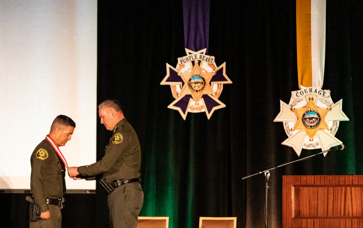 Orange County Sheriff Don Barnes presents a medal to Deputy Ronnie Garcia at the Hilton Hotel of Anaheim, Calif., on April 14, 2022. (John Fredricks/The Epoch Times)