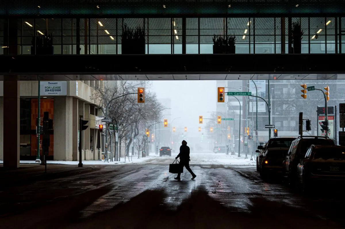 A man carrying a food delivery bag makes his way across York Avenue underneath a skywalk in Winnipeg on April 13, 2022. (The Canadian Press/Mike Sudoma)