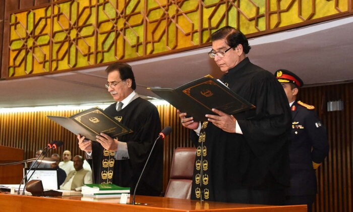Raja Pervaiz Ashraf (R), a former prime minister who belongs to the Pakistan Peoples Party (PPP) which is part of the new ruling alliance, takes oath as the 22nd Speaker of the National Assembly of Pakistan from Ayaz Sadiq, a member of the panel of the chairman, at the Parliament House in Islamabad, Pakistan, on April 16, 2022. (Press Information Department/Handout via Reuters)