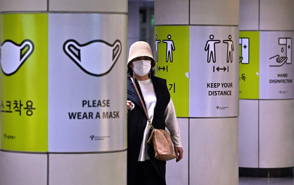 A woman walks past posters showing precautions against the COVID-19 coronavirus at a subway station in Seoul on April 15, 2022. (Jung Yeon-je/AFP via Getty Images)
