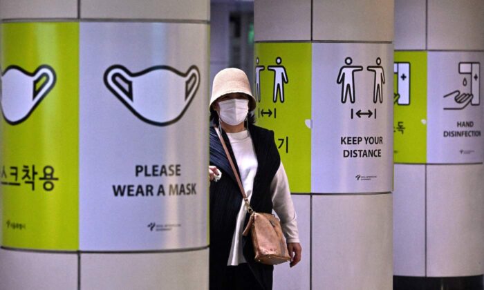 A woman walks past posters showing precautions against the COVID-19 coronavirus at a subway station in Seoul on April 15, 2022. (Jung Yeon-je/AFP via Getty Images)
