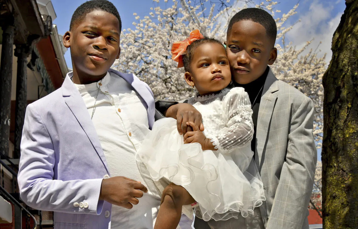 Dressed in their Easter best, ten-year old twin brothers Dominique, left, and Da'yonne Myers, holding their one-year old sister, J'Lynn Myers, pose for family pictures after church on April 4, 2021. (Amy Davis/Baltimore Sun/TNS)