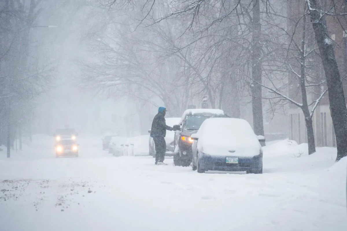 A man cleans snow off his car on Edmonton Street in Winnipeg on April 13, 2022. The same spring storm also battered northern Ontario, causing power outages and downing lines and poles. (The Canadian Press/Mike Sudoma)
