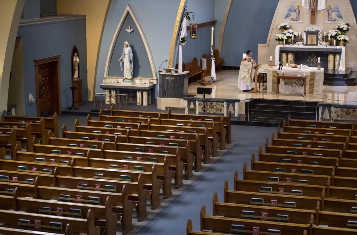 Empty pews are seen as Father Mark Goring, pastor at St. Mary's Parish Catholic church in Ottawa, delivers his homily in front of an iPhone broadcasting the Easter Sunday mass live on YouTube on April 12, 2020. (Justin Tang/The Canadian Press)
