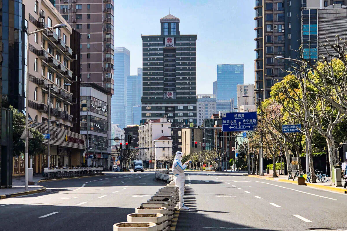 A worker in protective overall stands in the middle of empty streets in a lockdown area in the Jingan district of western Shanghai on April 4, 2022. (Chen Si/AP Photo)