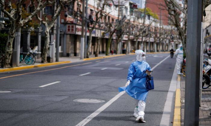 A worker in a protective suit keeps watch on the street as the second stage of a two-stage lockdown to curb the spread of COVID-19 begins in Shanghai, China, on April 1, 2022. (Aly Song/Reuters)