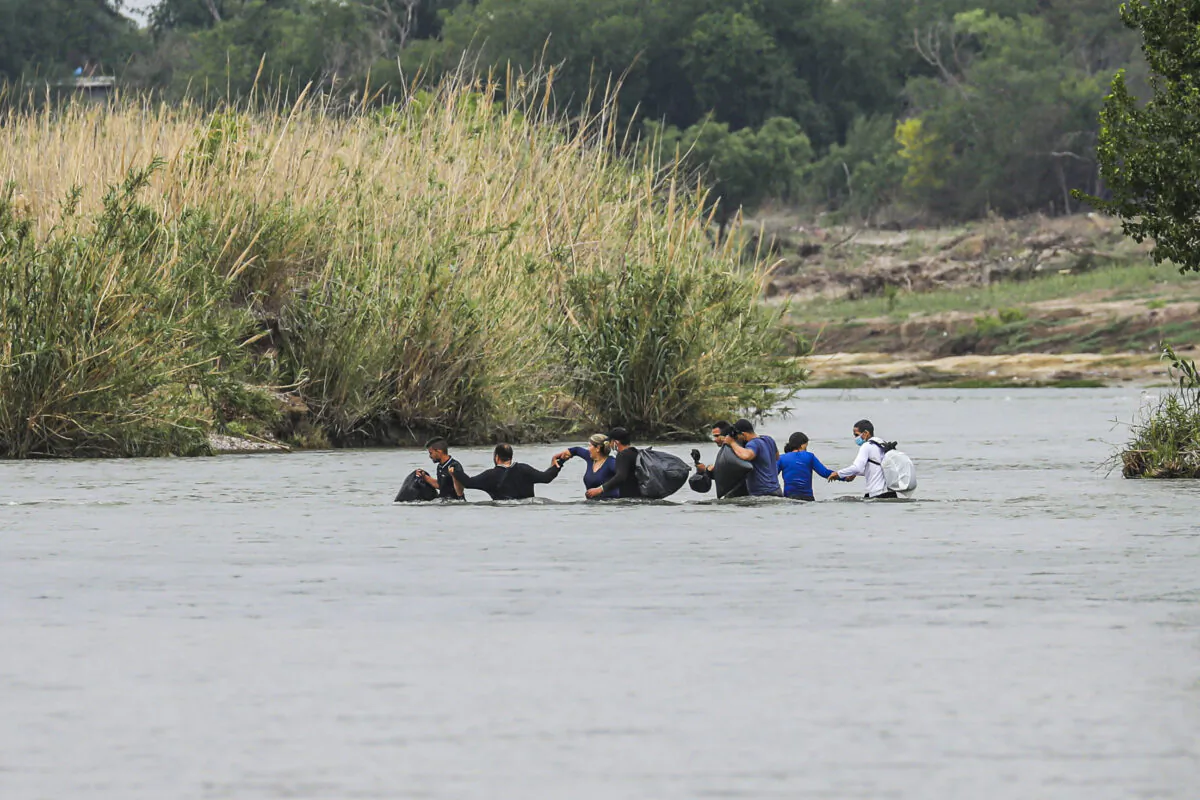 A group of Cubans wade across the Rio Grande from Mexico toward the United States in Eagle Pass, Texas, on April 19, 2022. (Charlotte Cuthbertson/The Epoch Times)