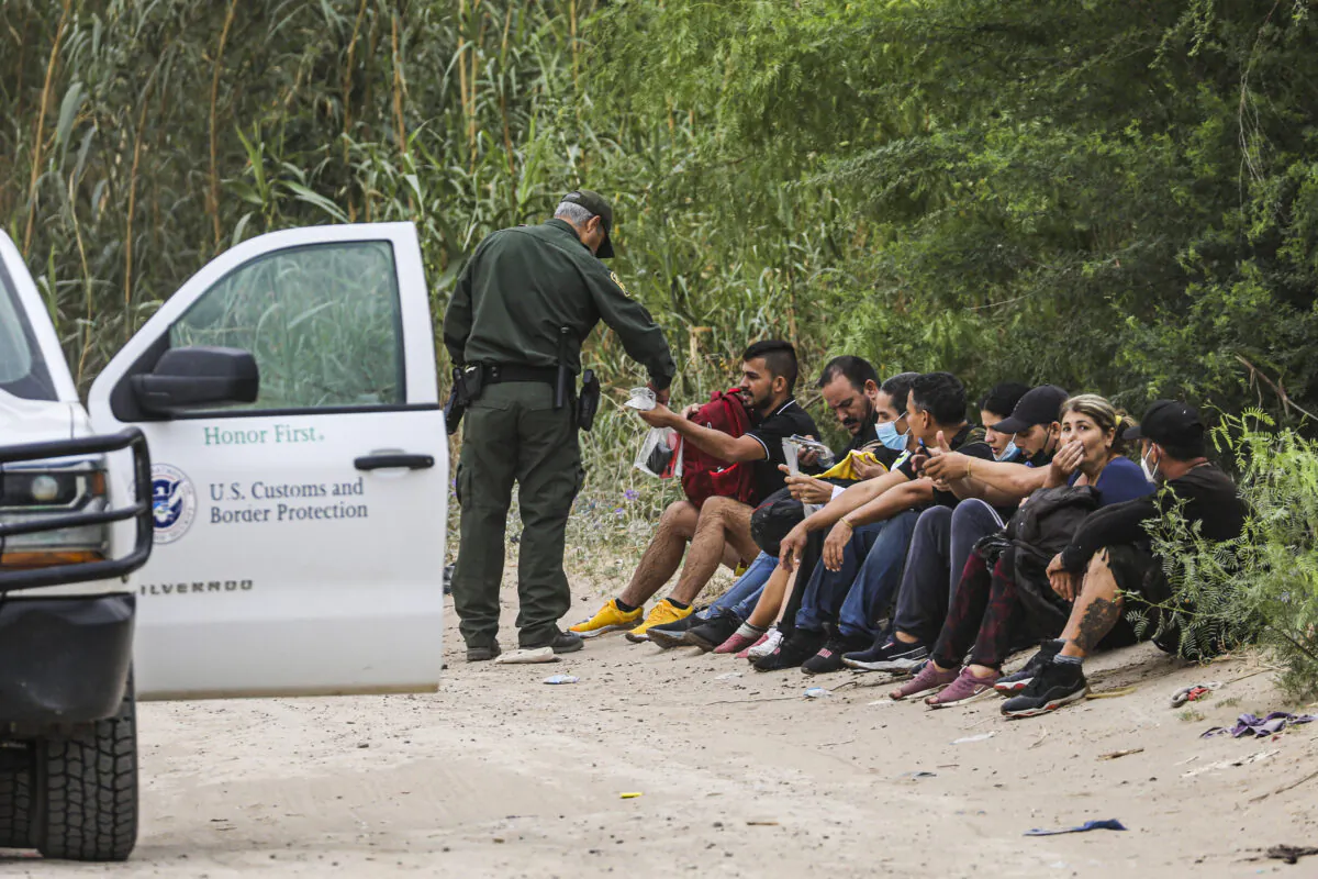 A Border Patrol agent apprehends a group of Cubans who just crossed the Rio Grande from Mexico into Eagle Pass, Texas, on April 19, 2022. (Charlotte Cuthbertson/The Epoch Times)