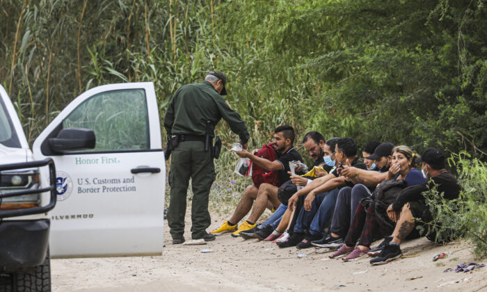 A Border Patrol agent apprehends a group of Cubans who just crossed the Rio Grande from Mexico into Eagle Pass, Texas, on April 19, 2022. (Charlotte Cuthbertson/The Epoch Times)